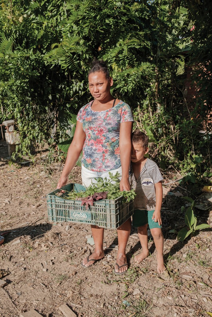 Maria Emilia Souza Antunes, 37, lives on Roseli Nunes with her two sons and husband. She holds a basket with branches of basil and hibiscus ready to be transported to the Armazém do Campo store in Rio de Janeiro for sale.