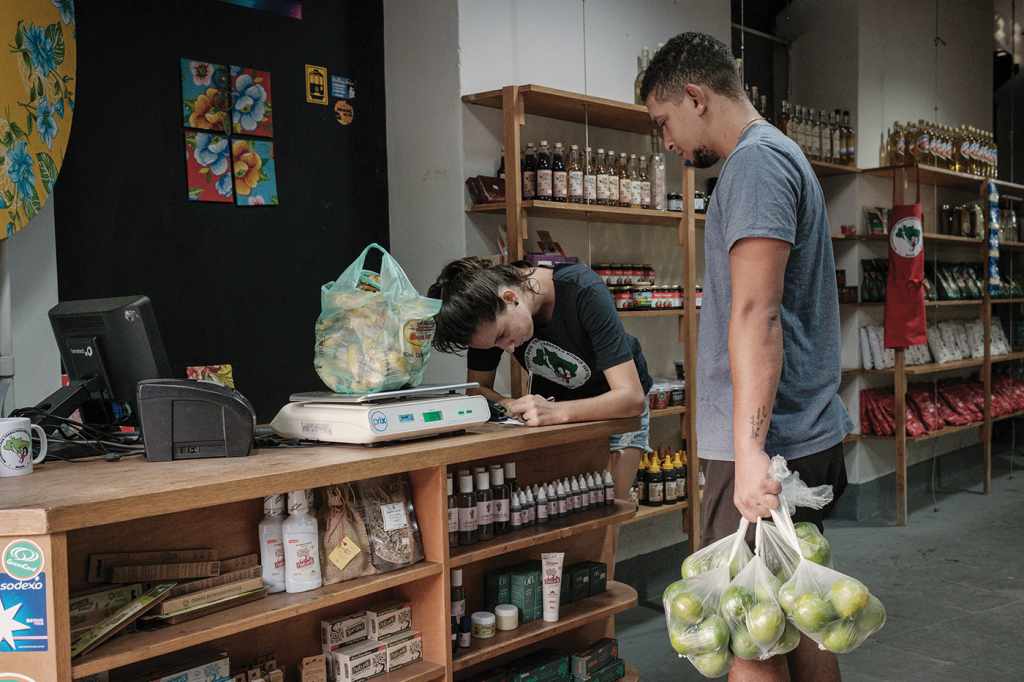 Two workers at the Rio de Janeiro Armazém do Campo store weigh and check food, including produce sold directly from MST settlements to urban populations. 