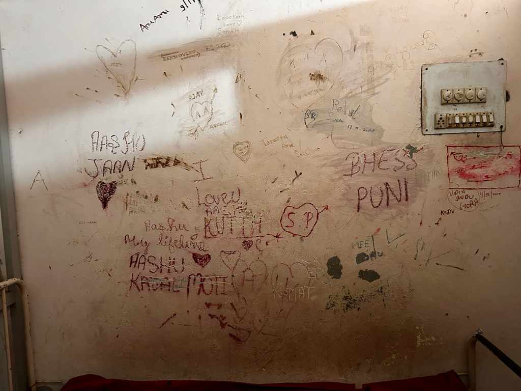 One of the walls in a safe home in Haryana features names carved and doodled by runaway couples. Names and hearts are carved into the wall. 