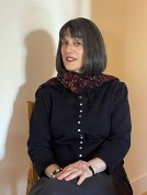 Nancy Kricorian sits on a chair with a coat on