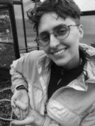 a person with glasses and short hair looks at the camera