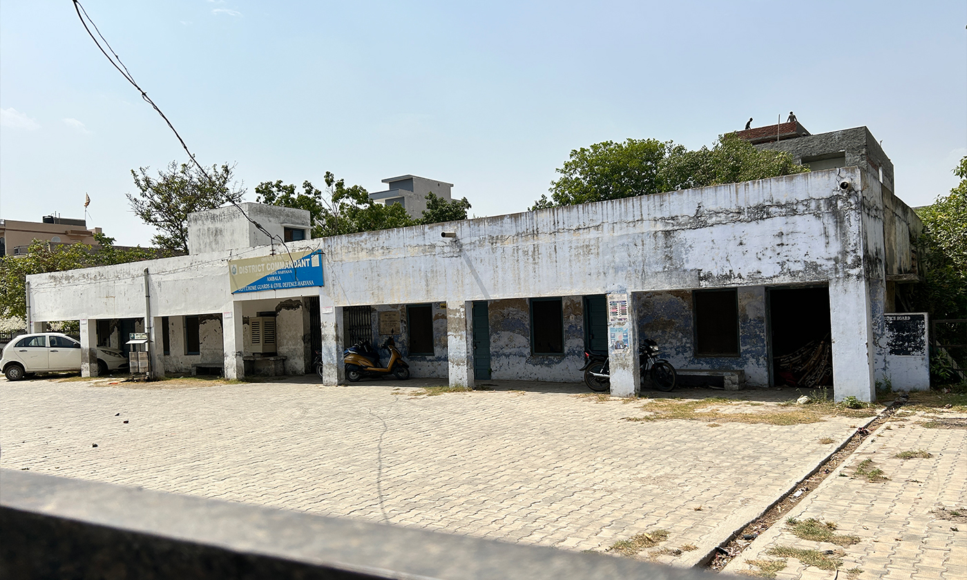 A photograph of a safe home in India, a nondescript concrete structure along a sidewalk.