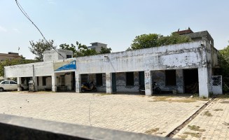A photograph of a safe home in India, a nondescript concrete structure along a sidewalk.