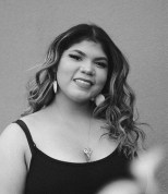 Kellian Staggers, a Black and Indigenous person with long curly hair, smiles at a camera