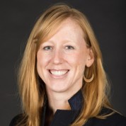 a white person with red hair looks and smiles at the camera