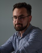 a person with lighter skin and glasses looks at the camera