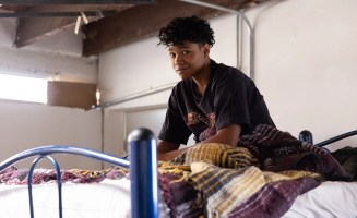 A teenager rests at a migrant shelter in the border city of Ciudad Juarez, just across the Rio Grande River from El Paso, Texas (Feb. 4, 2025). He sits on a bed and looks at the camera.