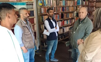 Three members of a prison cooperative in Argentina are in the prison library discussing their work with a journalist and a lawyer.