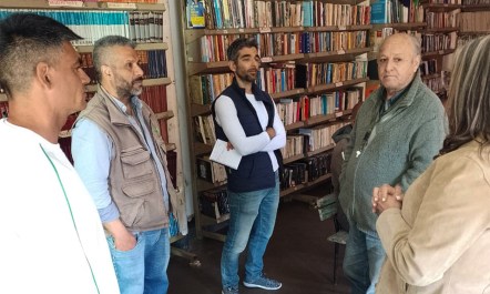 Three members of a prison cooperative in Argentina are in the prison library discussing their work with a journalist and a lawyer.